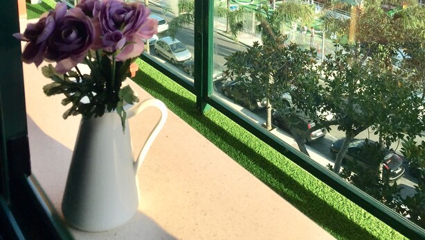 A balcony with a view of the sea, a white building, and a vase with purple flowers. - Luxury apartment Bajondillo on the beach (TORREMOLINOS)