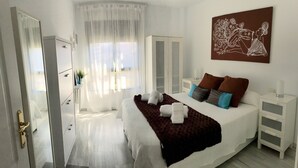A modern bedroom with a large bed, a bedside table, a nightstand, and a painting on the wall. - Luxury apartment Bajondillo on the beach (TORREMOLINOS)