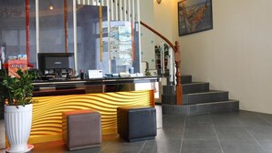A hotel reception area with a modern design, featuring a reception desk, a staircase, and a framed artwork on the wall. - Hang Hai B & B (Hengchun)