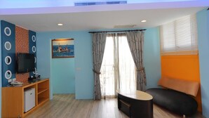A room with a TV, a small fridge, a sofa, and a painting on the wall. - Hang Hai B & B (Hengchun)