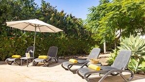 A patio area with lounge chairs, a table, and an umbrella.