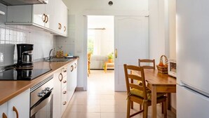 A modern kitchen with white cabinets, a black countertop, and a dining area with wooden furniture.