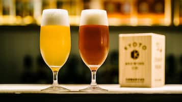 Two glasses of beer on a bar counter with a wooden box in the background.