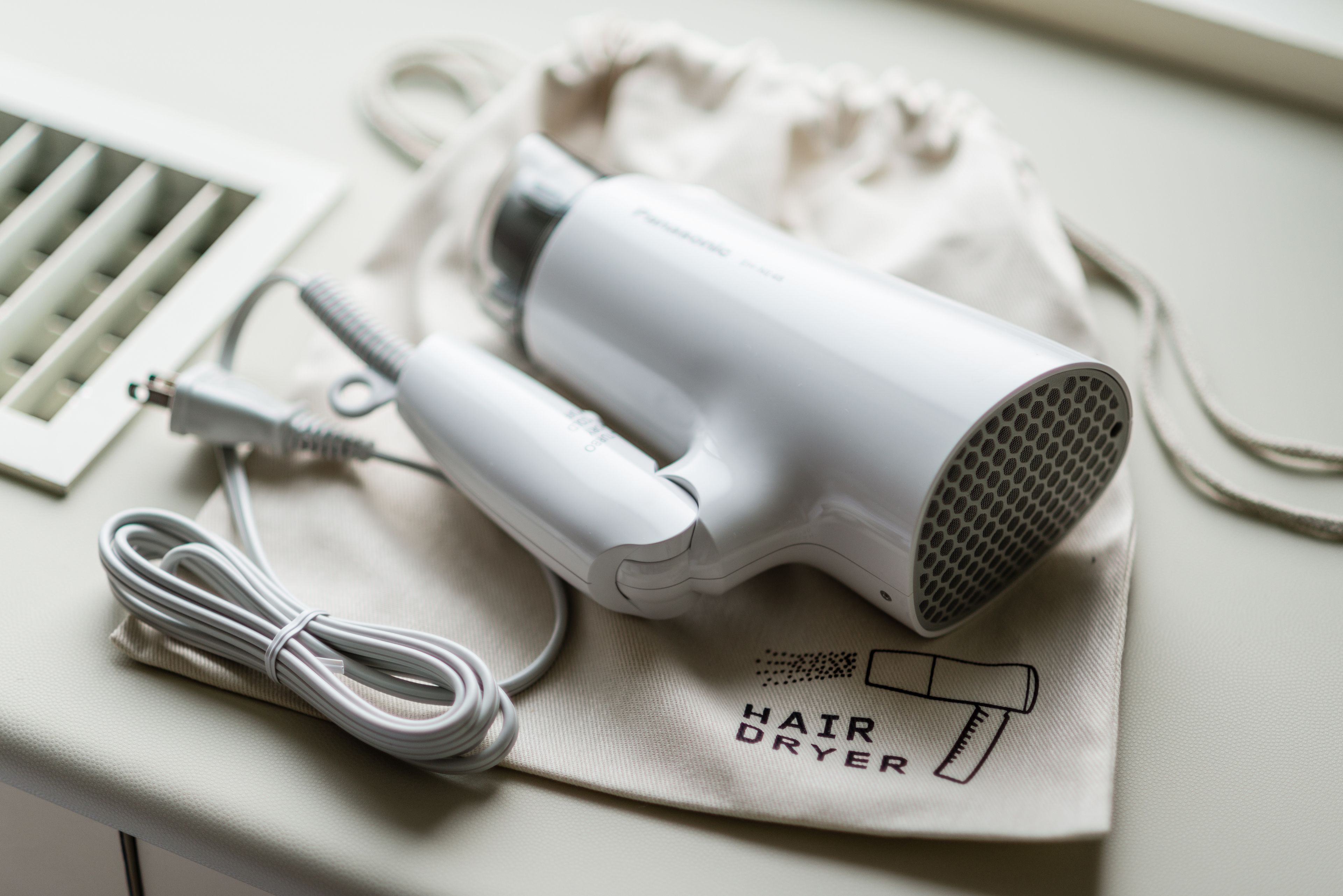 A hair dryer and its accessories on a beige surface.