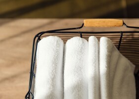 Un portaobjetos metálico con un asa de madera que sostiene varias toallas blancas.