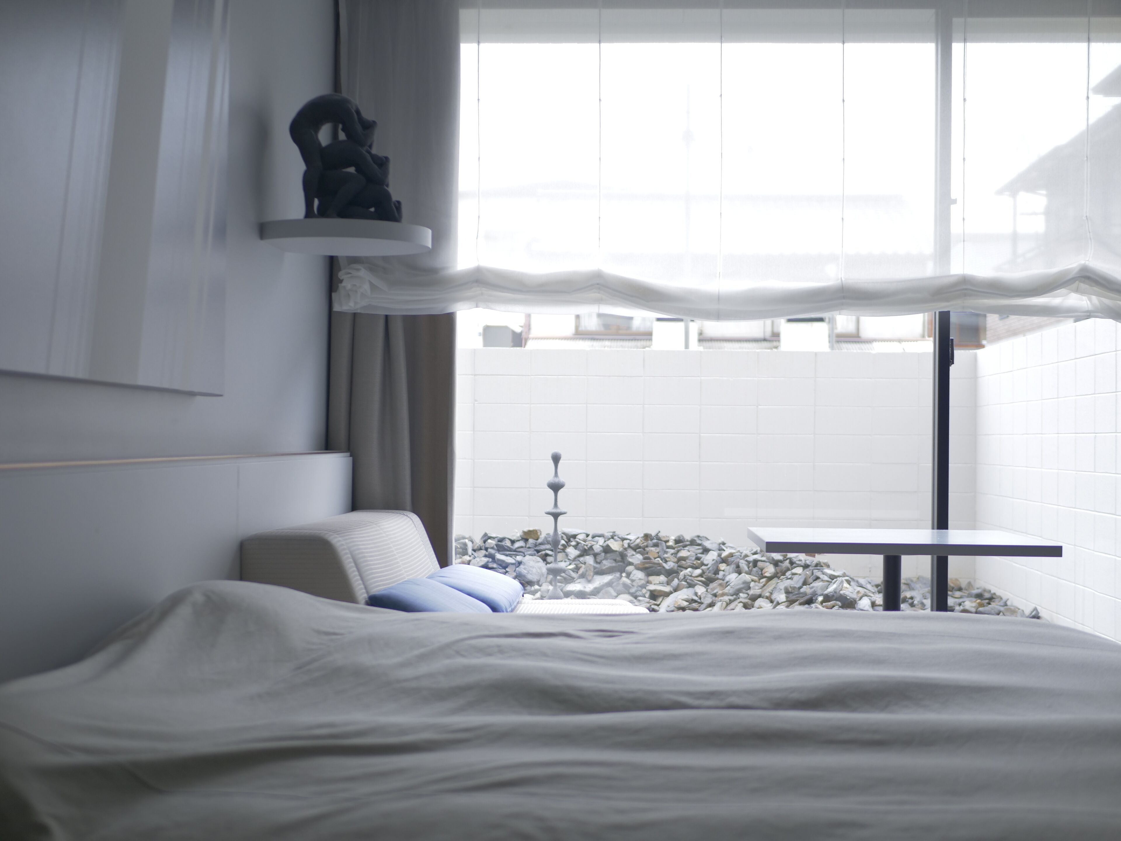Habitación de hotel moderna con cama, una mesita y vistas a un paisaje urbano a través de amplios ventanales.