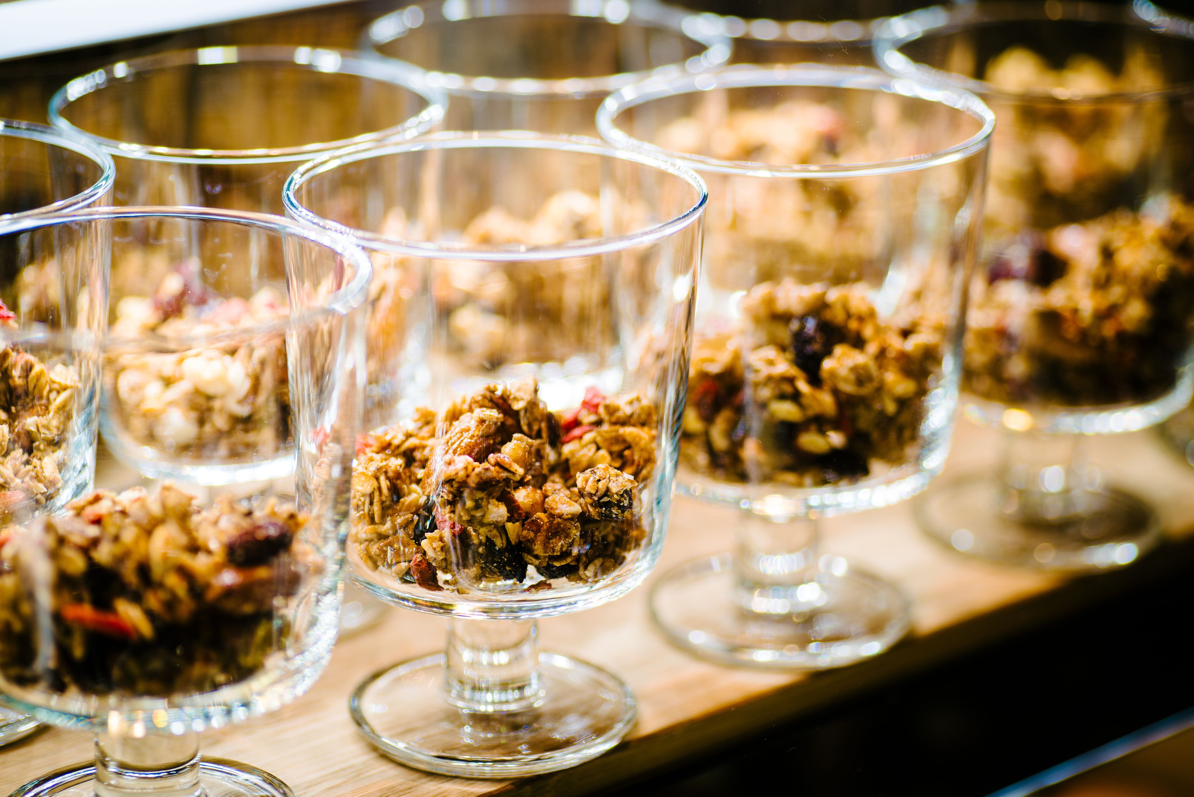 A series of clear glass dessert cups on a wooden surface.
