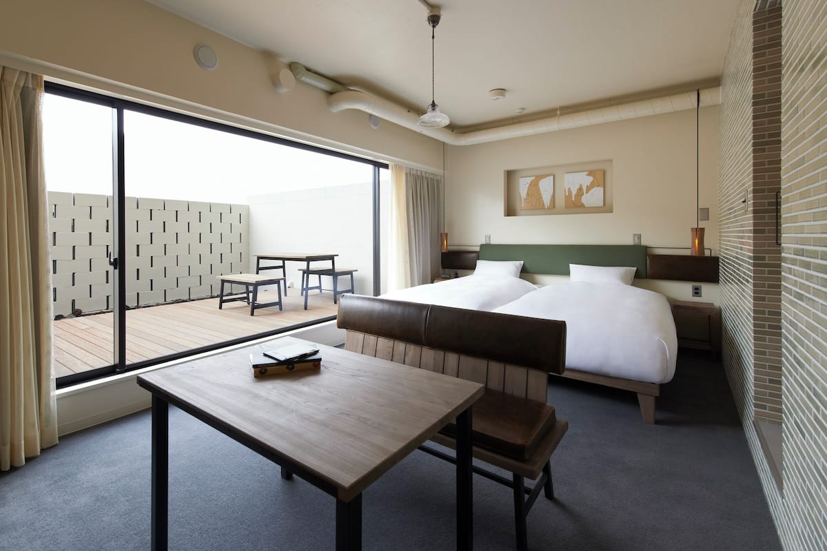 Habitación de hotel con cama, escritorio, silla, mesa, ventana y vistas al exterior.