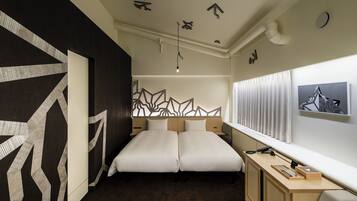 Una cama doble con un diseño geométrico en la pared, un escritorio con una lámpara y una ventana con cortinas.