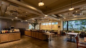 Een ruim restaurant met een centraal eiland, houten tafels en hangende pendelverlichting.