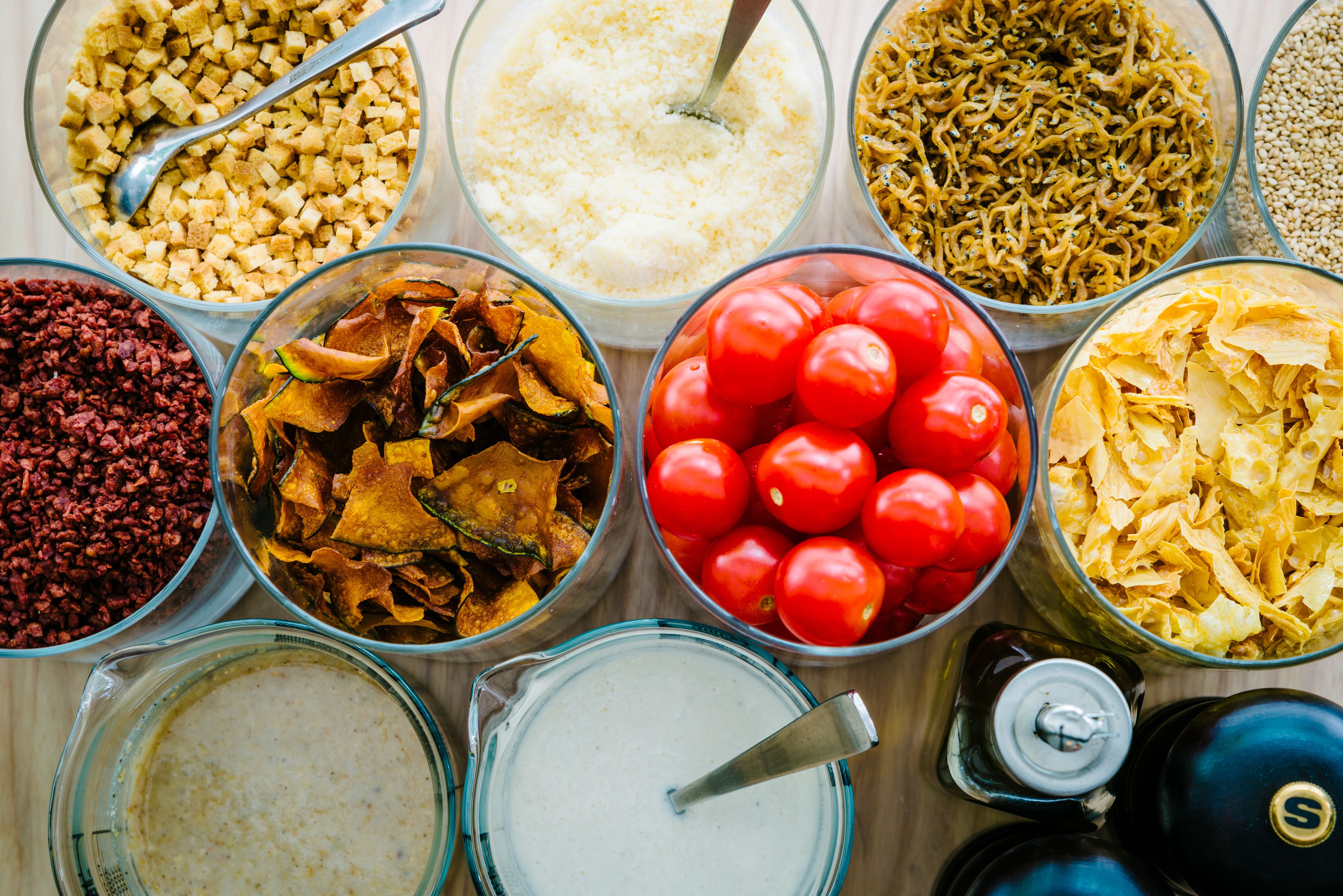 A variety of food items in glass bowls, including tomatoes, dried vegetables, and grains.
