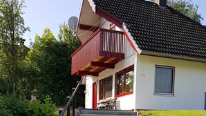 Una escalera que lleva a una casa con un balcón rojo y una chimenea.