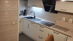 Una cocina compacta con un lavabo, cafetera y armarios.
