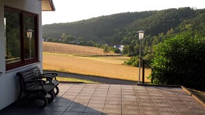 Un patio con una banca y vistas a un campo y colinas.