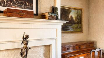 A room with a fireplace, a desk, and two framed paintings.