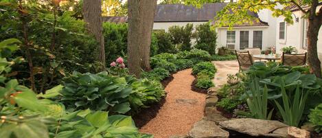 A garden pathway leading to a house with a patio area.