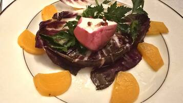 Un plato con ensalada, incluyendo hojas verdes, algo rosado y gajos de naranja.