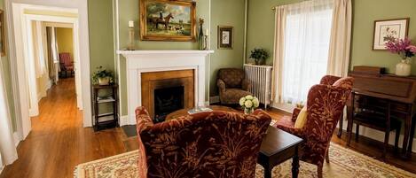 A living room with a fireplace, a dining table, and patterned chairs.