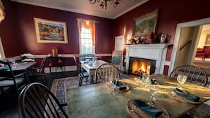 Une salle à manger avec une cheminée, un tableau et une vue sur l’extérieur.