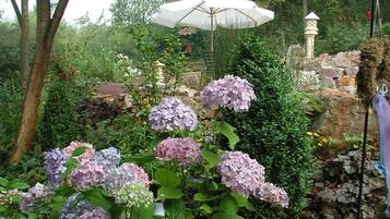 A garden with hydrangea bushes and a white umbrella.