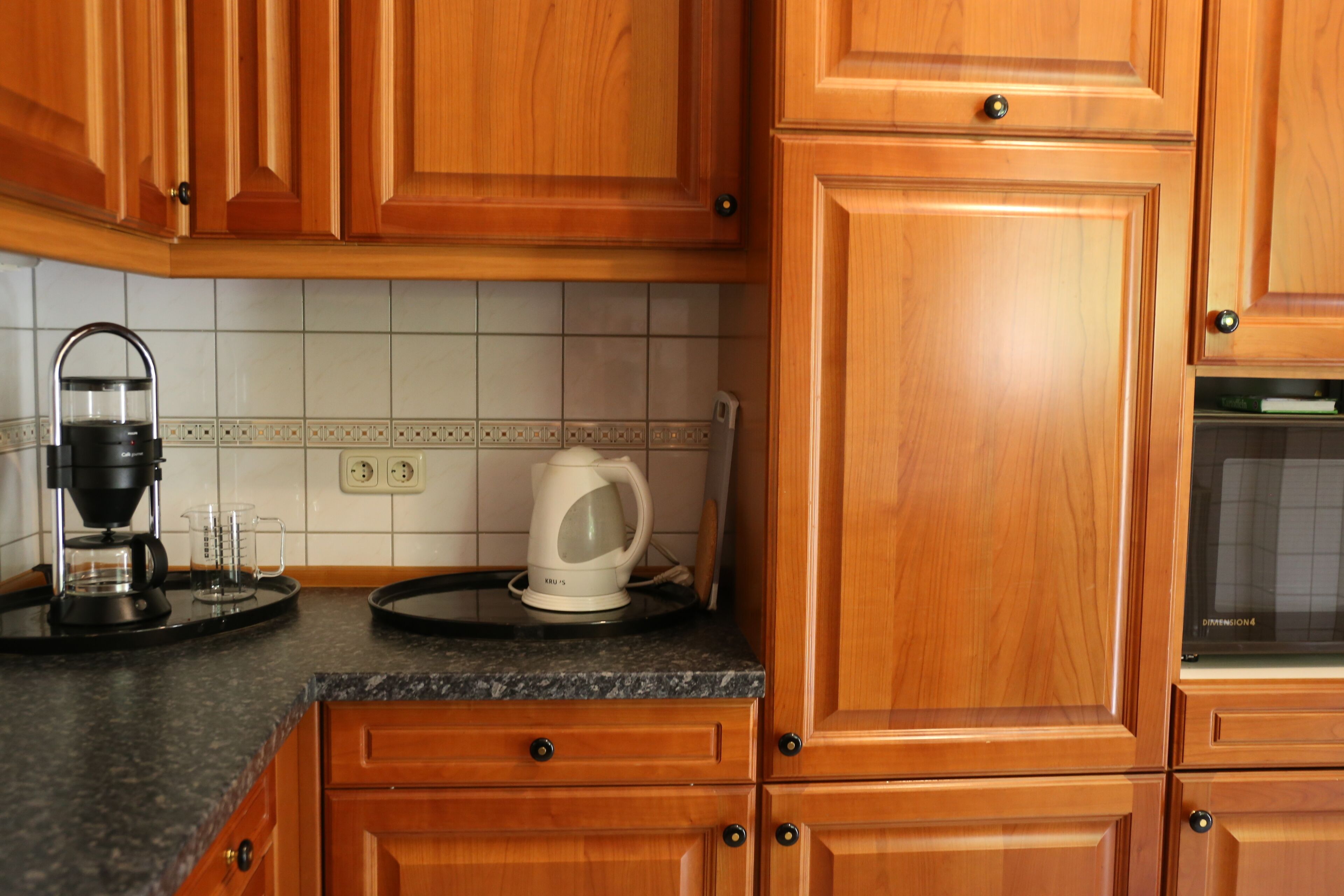 Una cocina con armarios de madera, una cafetera y un hervidor sobre la encimera.