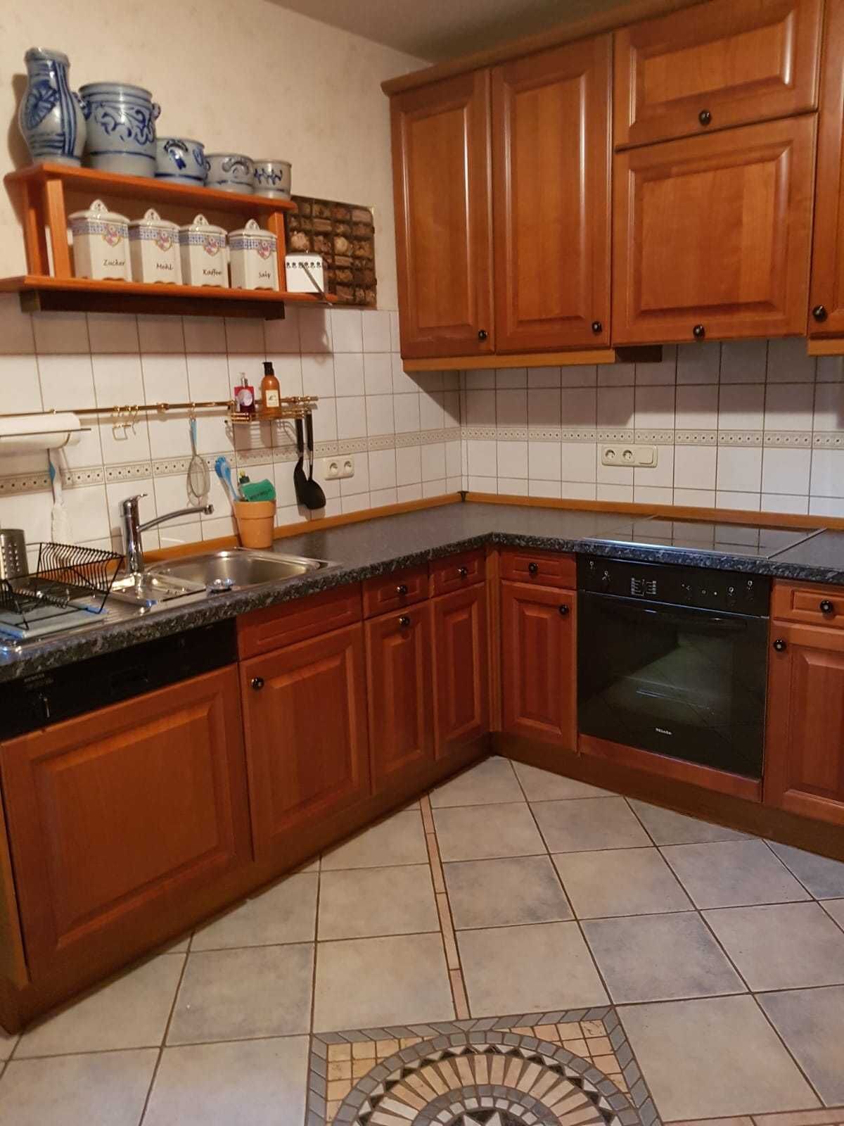 Eine Küche mit Holzschränken, einer Granitarbeitsplatte, einem Geschirrspüler und einem Herd.