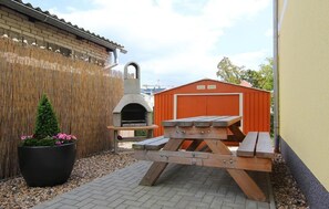 A patio area with a barbecue grill, a wooden picnic table, and a potted plant. - Morgenstern fantastic holiday (Göhren)