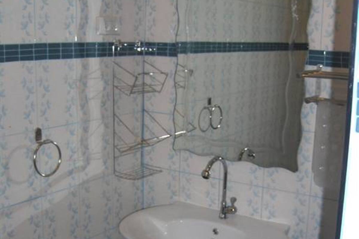 A bathroom with a white sink, a mirror, and a trash bin.