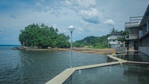 Un hôtel situé au bord de l’eau, doté d’une piscine, d’un lampadaire et offrant une vue sur la mer et la verdure.