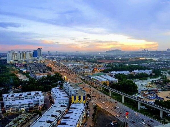A cityscape with a highway, buildings, and a sunset. - Puchong 1-5pax IOI Cozy Apartment Skypod (Puchong)