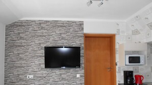 Eine moderne Küche mit Steinwand, Flachbildfernseher, Holztür und Mikrowelle.