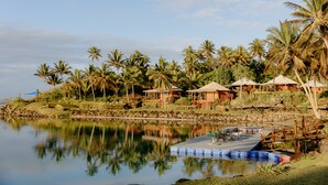 A lakeside resort with wooden cabins, palm trees, and a dock. - La Dolce Vita Holiday Villas (Savusavu)