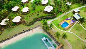 An aerial view of a resort with multiple bungalow-style accommodations, a swimming pool, and a dock leading to a beach. - La Dolce Vita Holiday Villas (Savusavu)