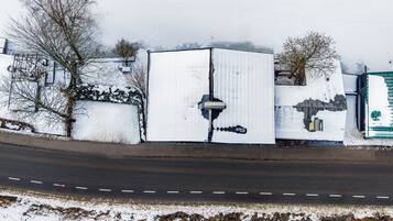 A snow-covered building adjacent to a road, with a visible security camera and a green gate.