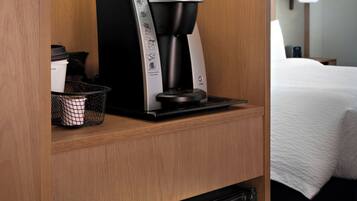 A compact kitchenette with a Keurig coffee maker, a small refrigerator, and a microwave on a wooden shelf.