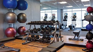 Een sportschool met trainingsapparatuur, loopbanden en fitnessballen.