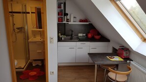 A compact kitchen with a sink, countertop, and a small dining table with chairs.