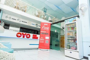 A hotel reception area with a large OYO Free sign, a digital screen, and a beverage vending machine. - OYO 394 Nana Beach Cha Am (Cha-am)