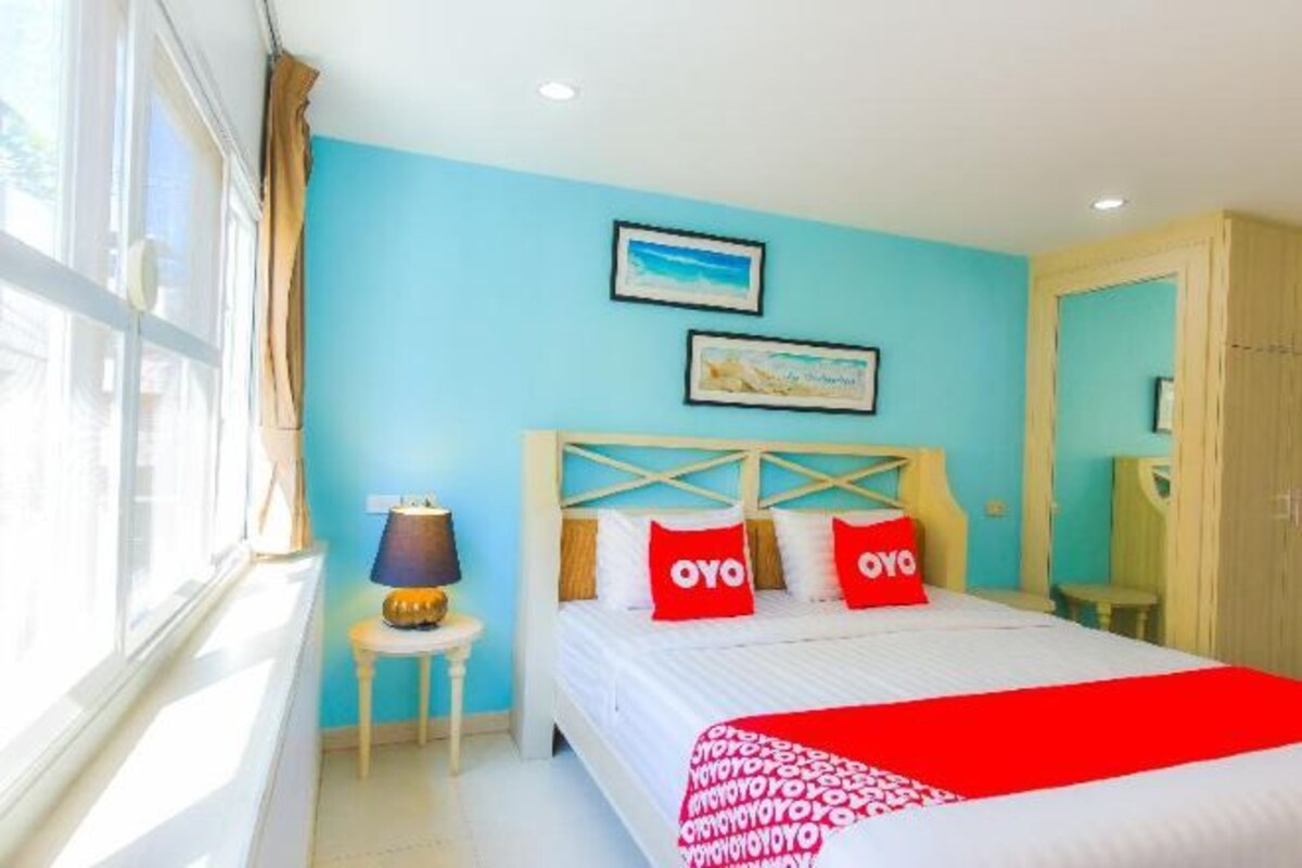 Una habitación de hotel con una cama, una mesita de noche, una lámpara y dos cuadros en la pared.