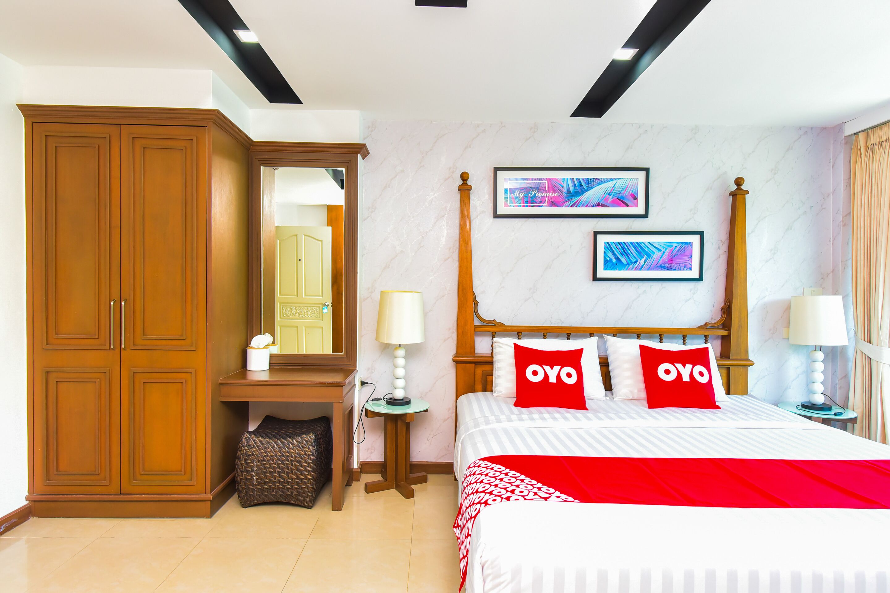 A hotel room with a bed, a wardrobe, a desk, and a mirror.