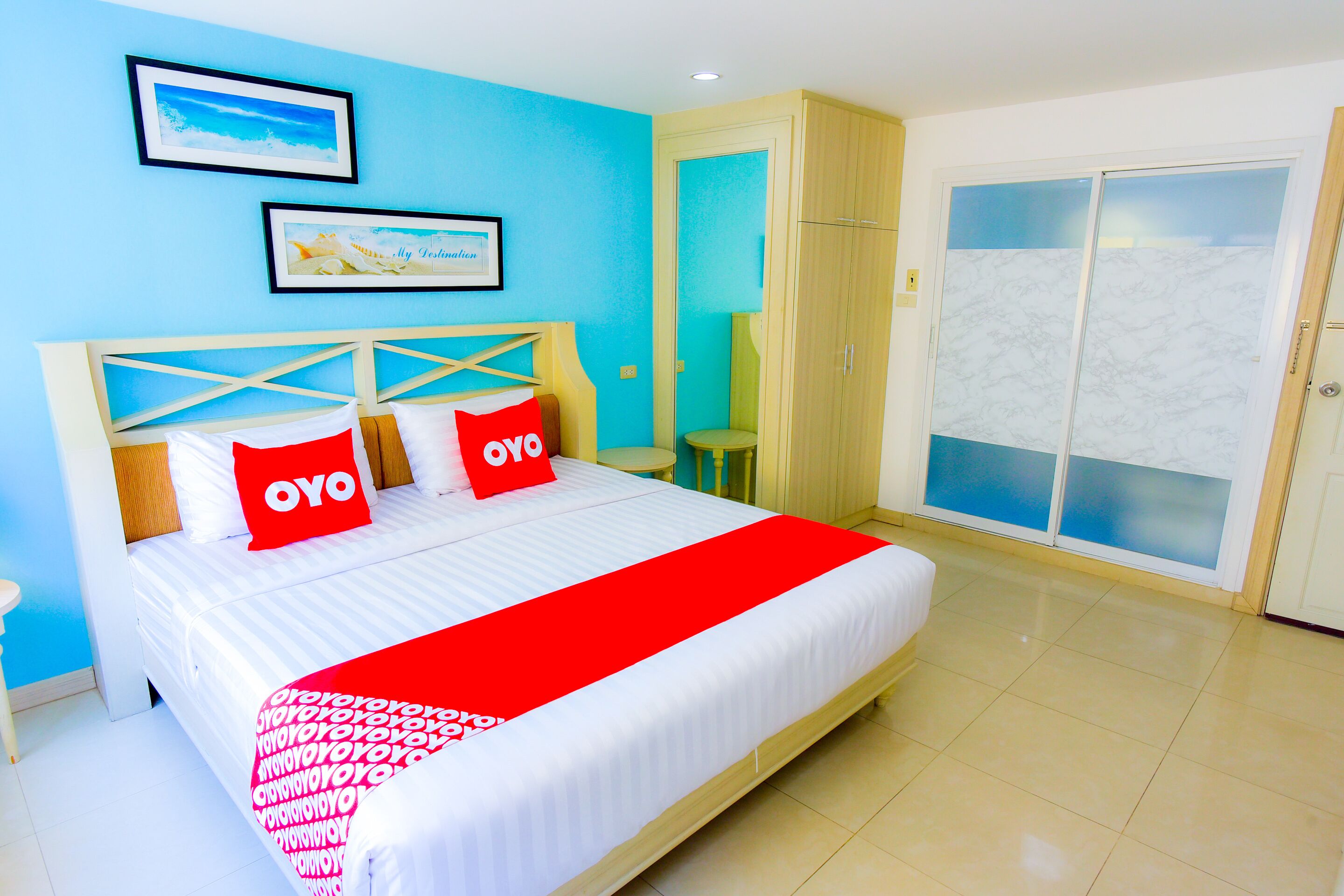 A hotel room with a bed, a wardrobe, a small table, and a door with frosted glass panels.