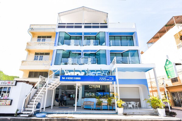 Un edificio de varios pisos con fachada azul y blanca, un escaparate visible con un letrero que dice "The Answer" y una escalera que lleva a la entrada.