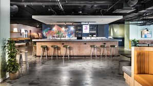 Zona de bar moderna con una barra central, taburetes y un área de estar con un sofá.