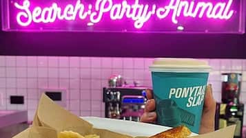 A tray with a grilled cheese sandwich and a banana, held by a hand with a cup labeled "Ponytail Slap".