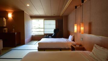 A hotel room with a bed, a chair, a bedside table, and a window with blinds.