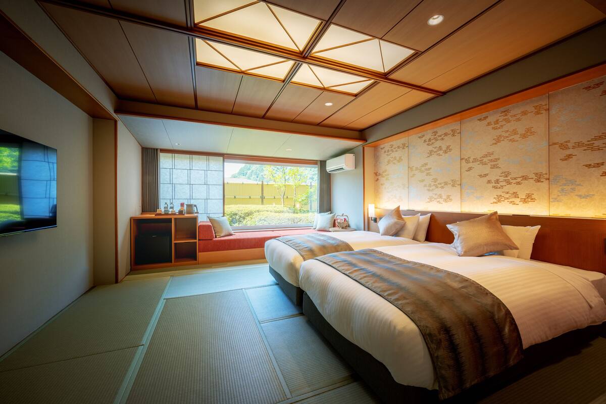 Ein Hotelzimmer mit einem großen Bett, einem Schreibtisch und Blick auf Grünfläche.