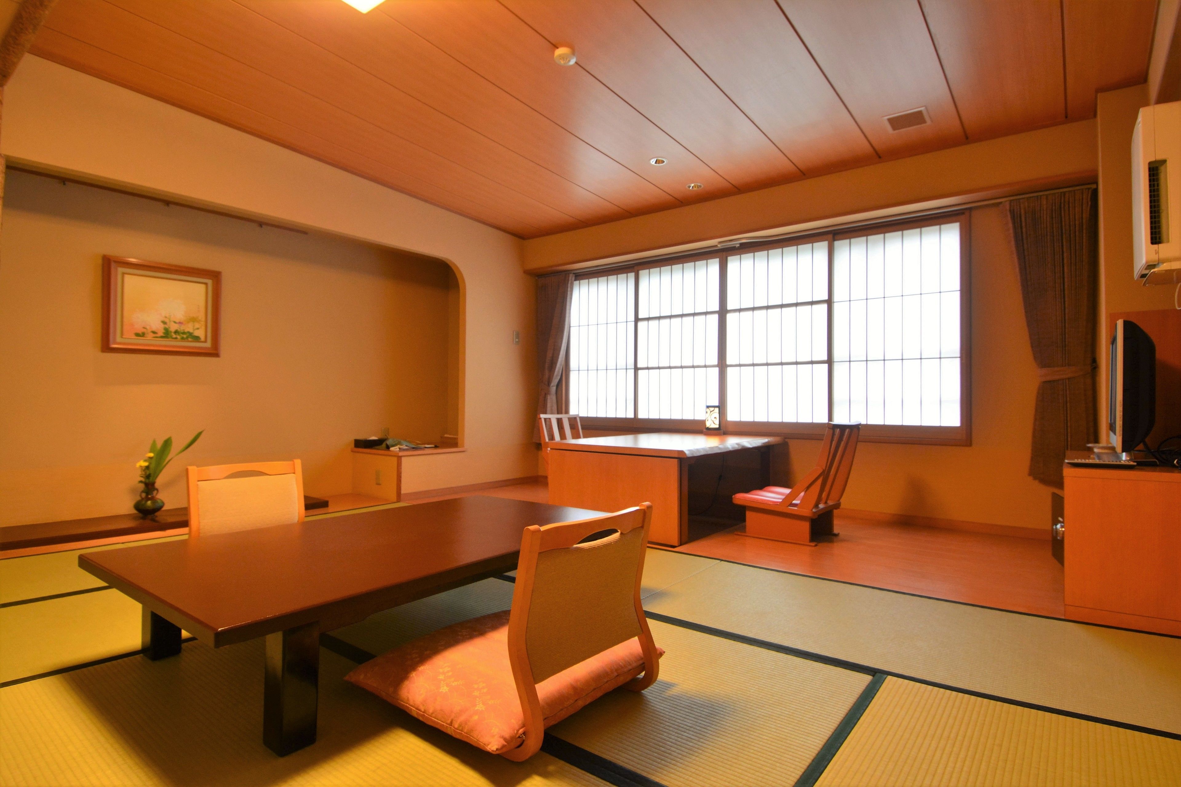 Um quarto japonês tradicional com tatames, uma mesa baixa e assentos.