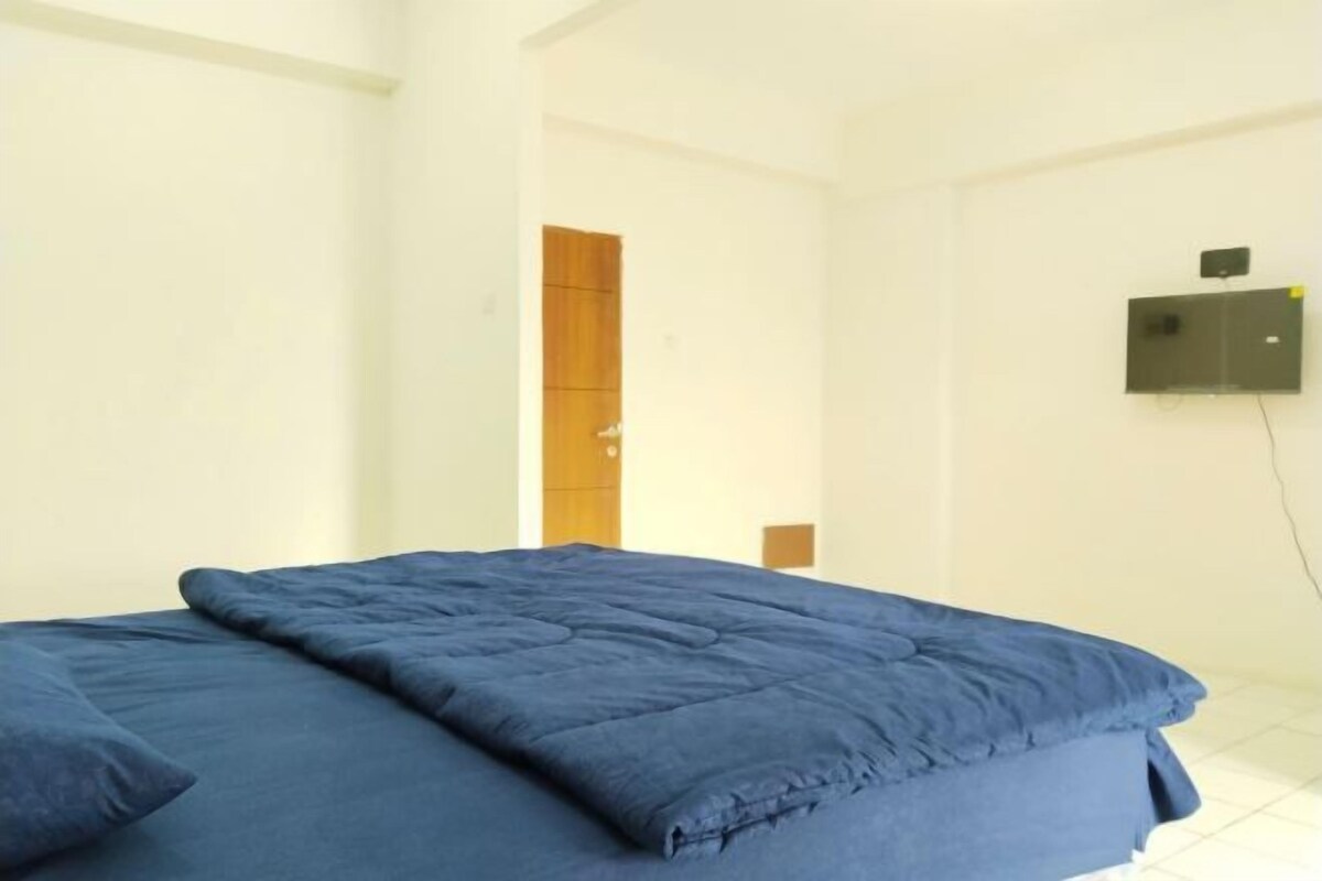 A room with a bed, a wooden door, and a wall-mounted device.