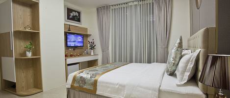 Un dormitorio moderno con una cama grande, televisión, escritorio y armario.