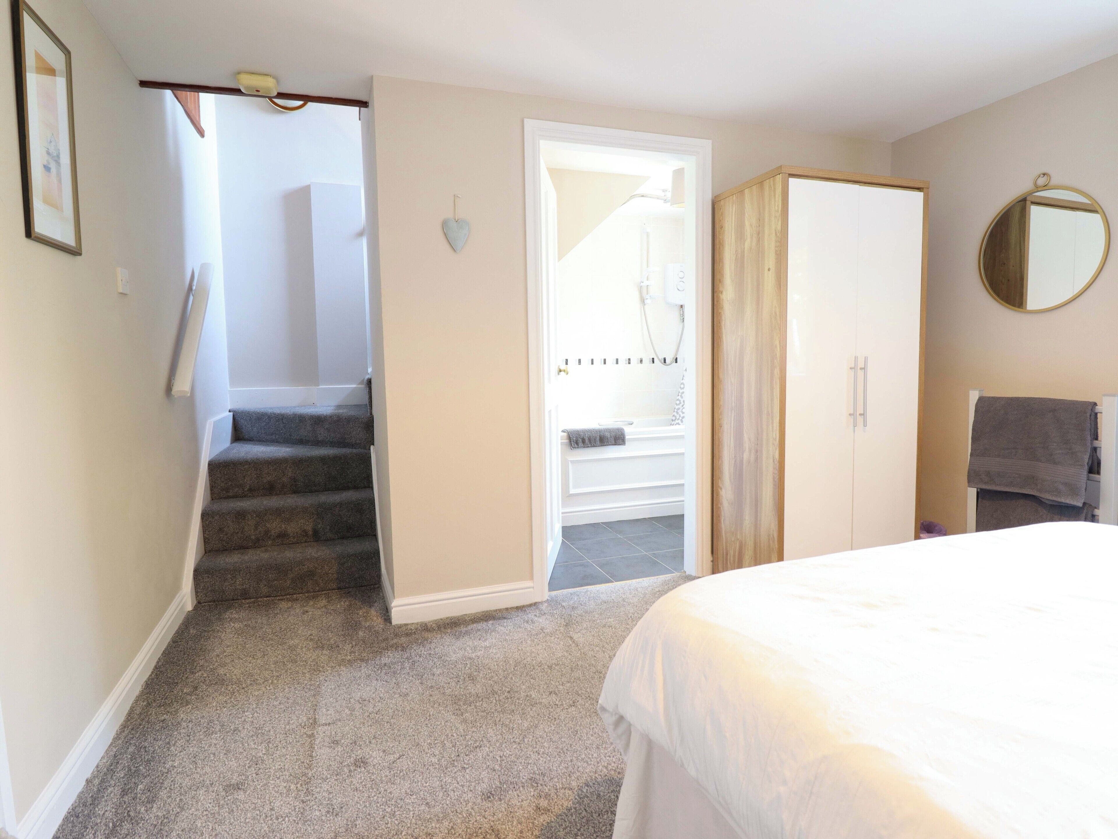 A bedroom with a bed, a wardrobe, a bathroom with a shower, and a staircase.
